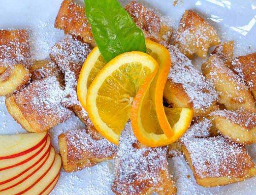 Gastro Kaiserschmarrn mit Puderzucker und Apfelscheiben serviert mit Orangenscheibe als Garnitur